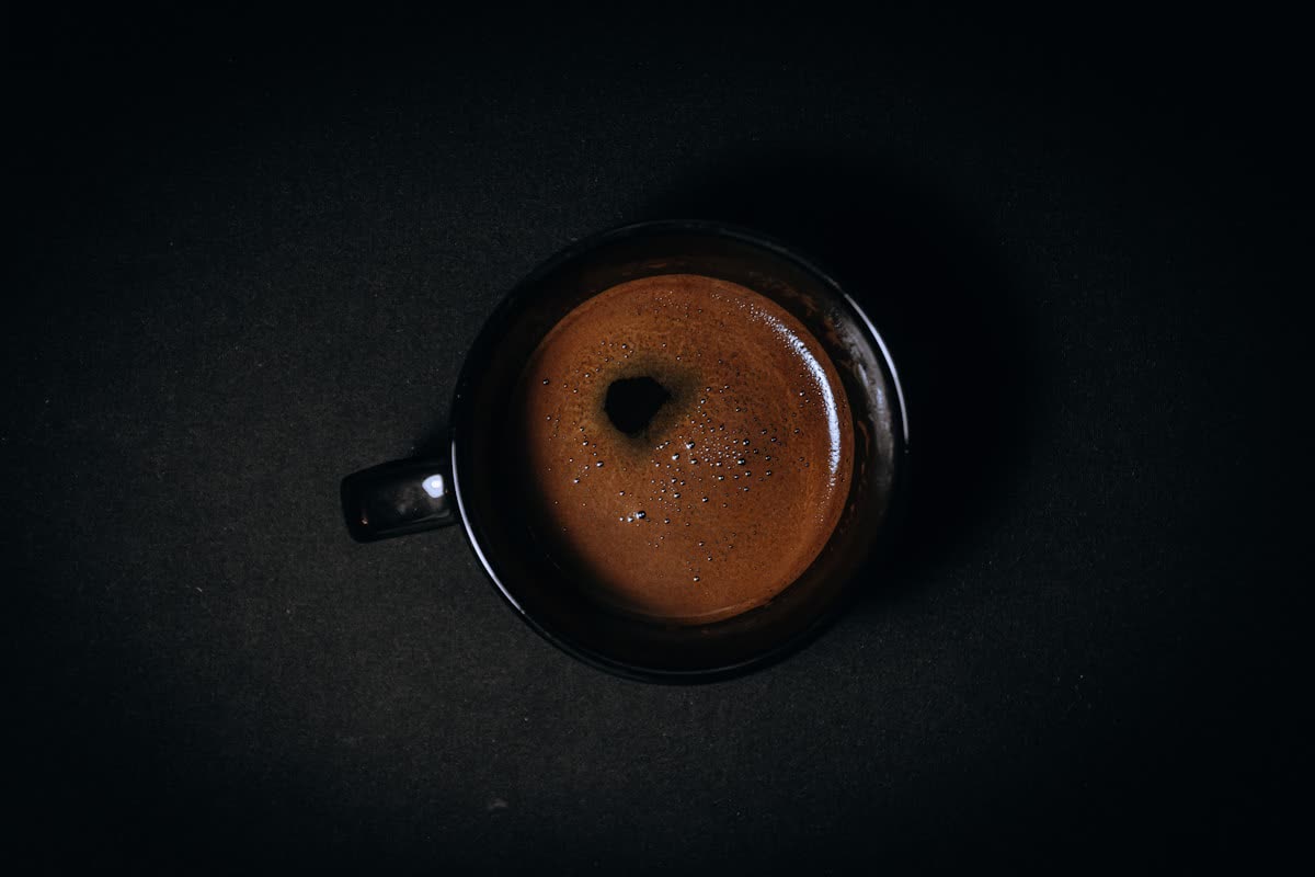 A finished beverage served with precision on a dark table setting.