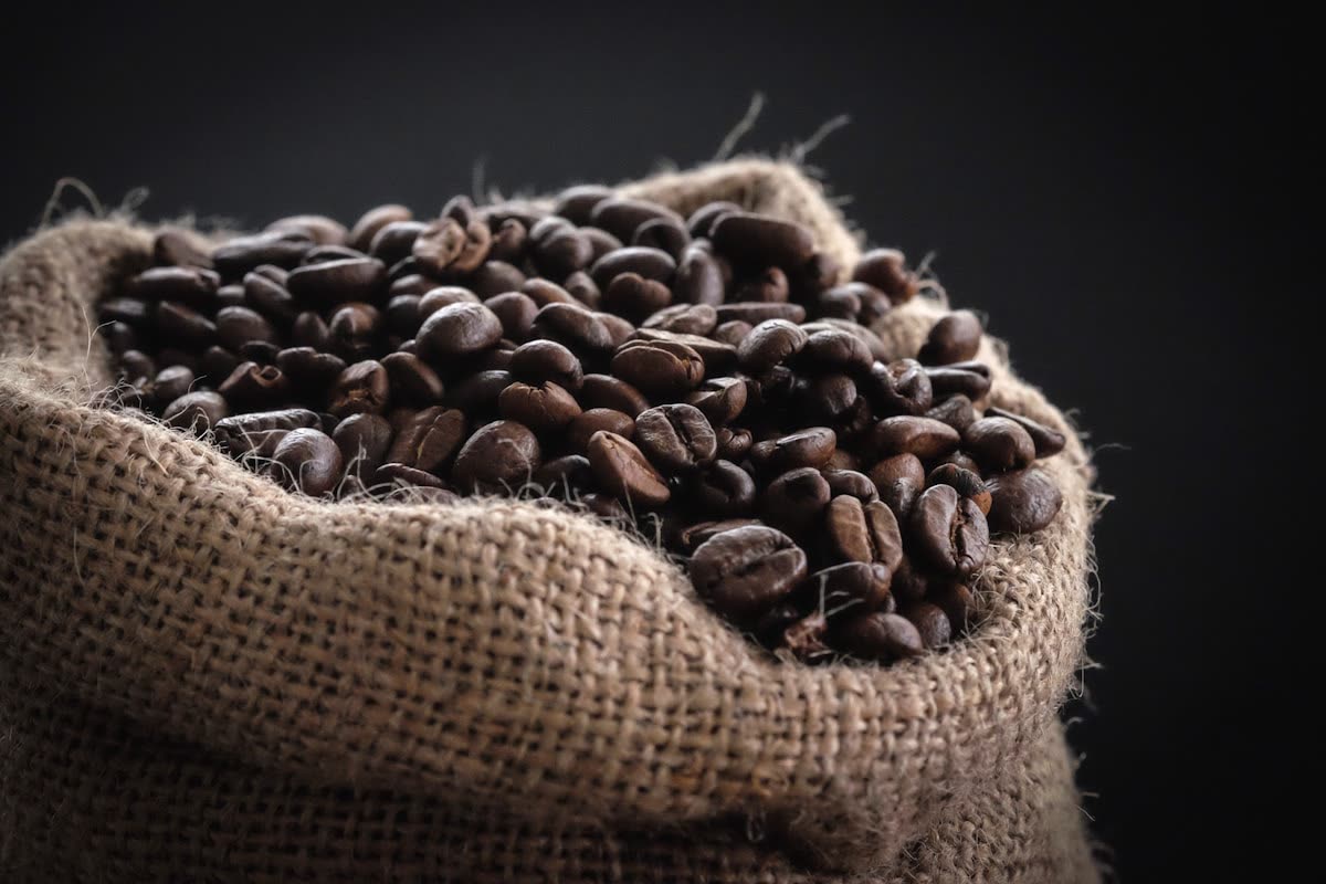 Raw green coffee beans, whole leaf and grain massed in commodity volume.